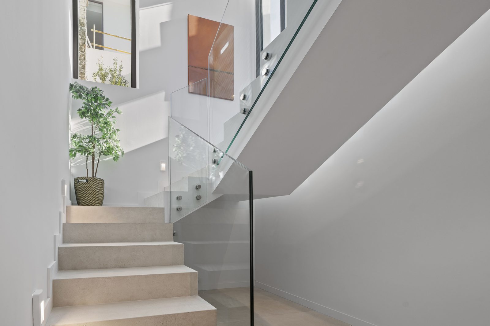 Modern staircase design with glass railings and a potted plant inside a 4-bedroom villa in Benidorm - The Estates