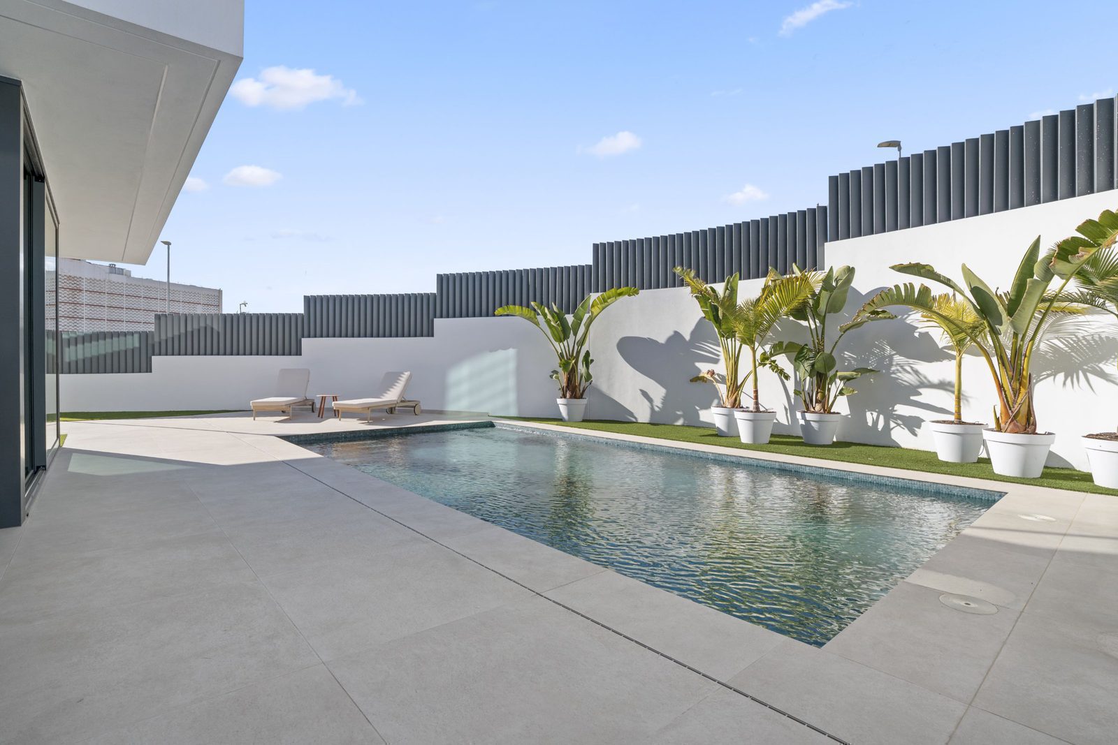 A modern pool area with palm trees at a 4-bedroom villa in Benidorm - The Estates