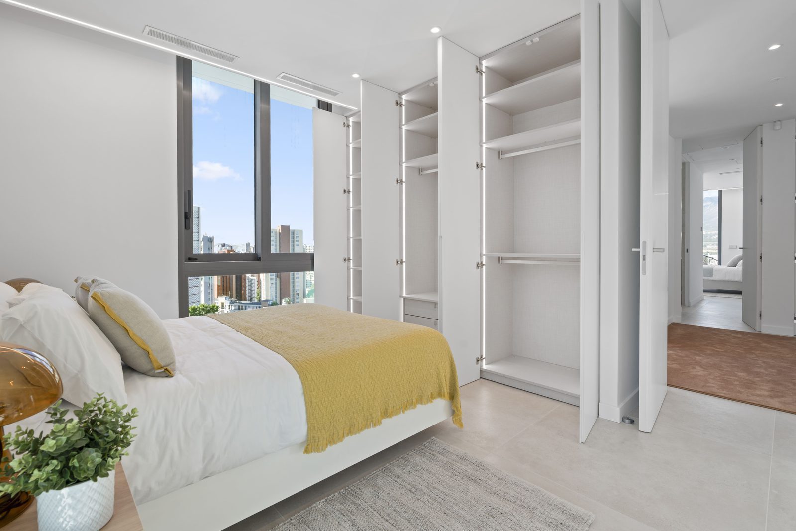 A modern bedroom with built-in wardrobes and city views in a 4-bedroom villa in Benidorm - The Estates