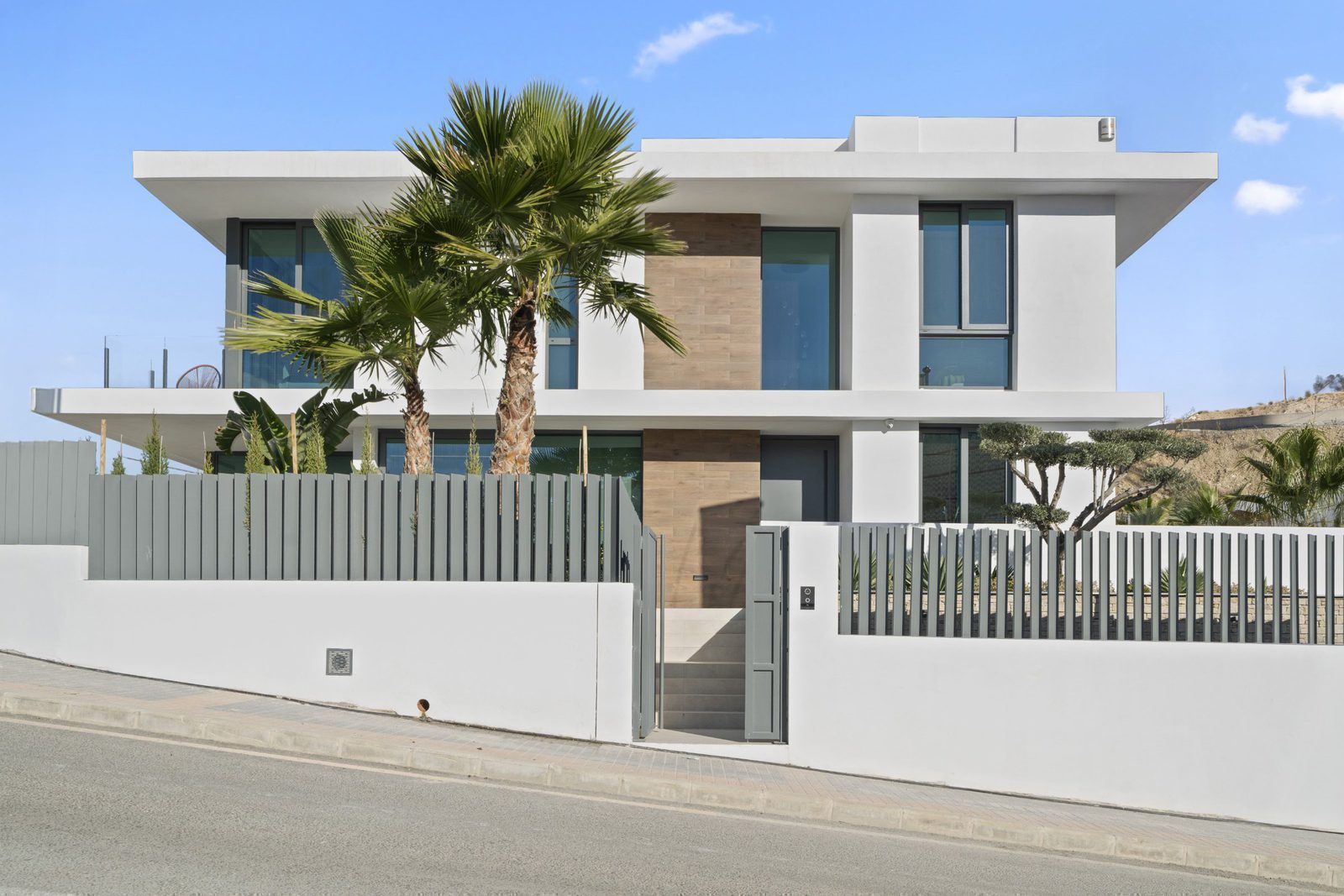 Modern exterior of a 4-bedroom villa in Benidorm with palm trees and city/sea views - The Estates