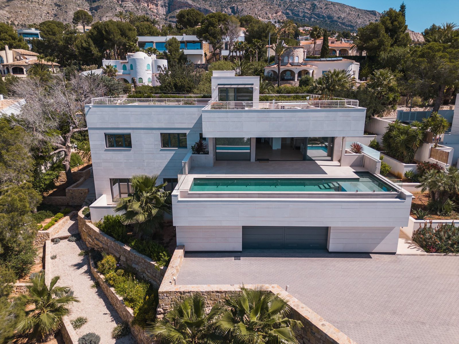 An elevated view of a modern villa with a pool and surrounding greenery in Altea - The Estates