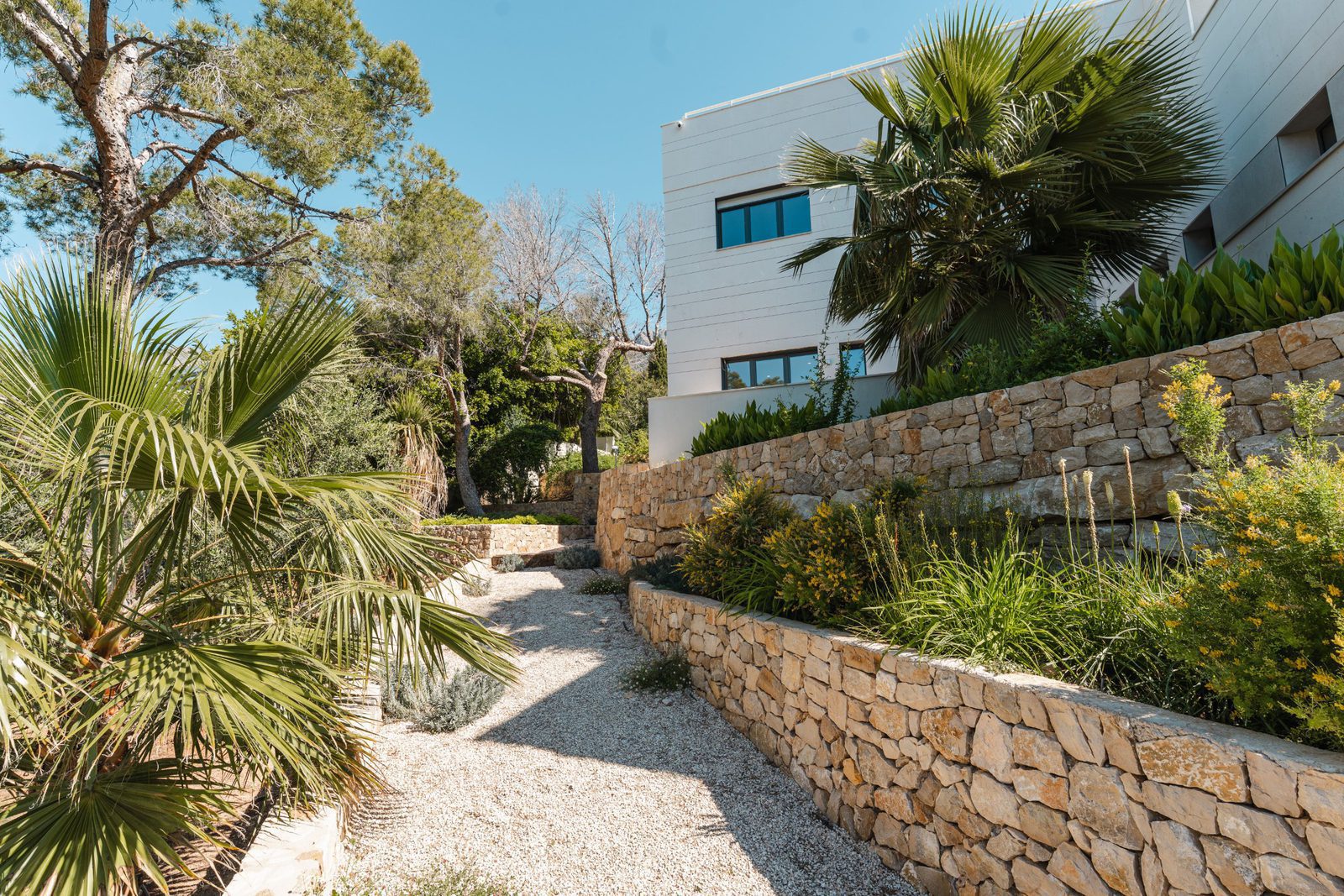 Lush gardens and stone walls surround a modern villa in Altea - The Estates