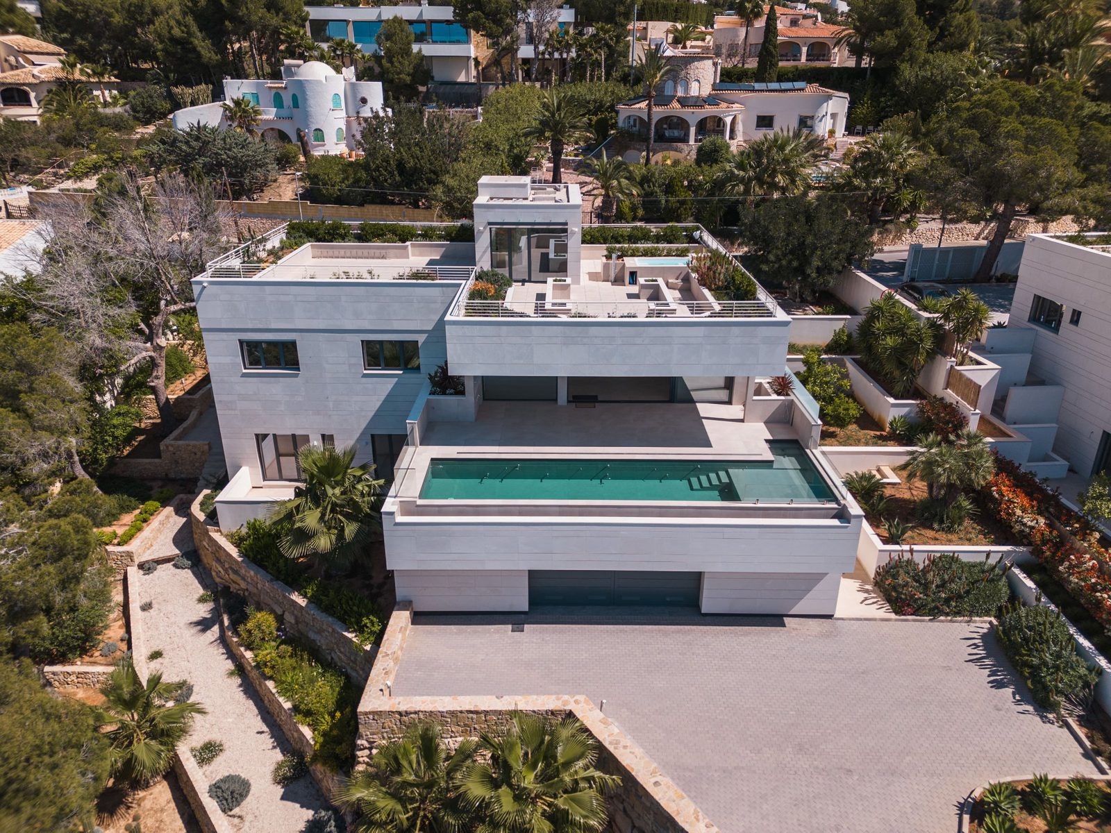An aerial view of a modern 5-bedroom villa with a pool and lush greenery in Altea - The Estates