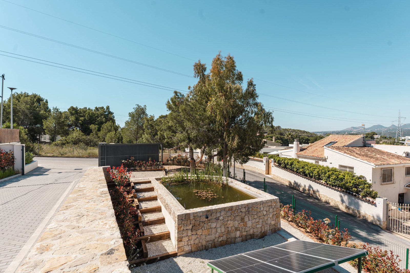 A tranquil garden with a pond and solar panels at a 5-bedroom villa in Altea - The Estates