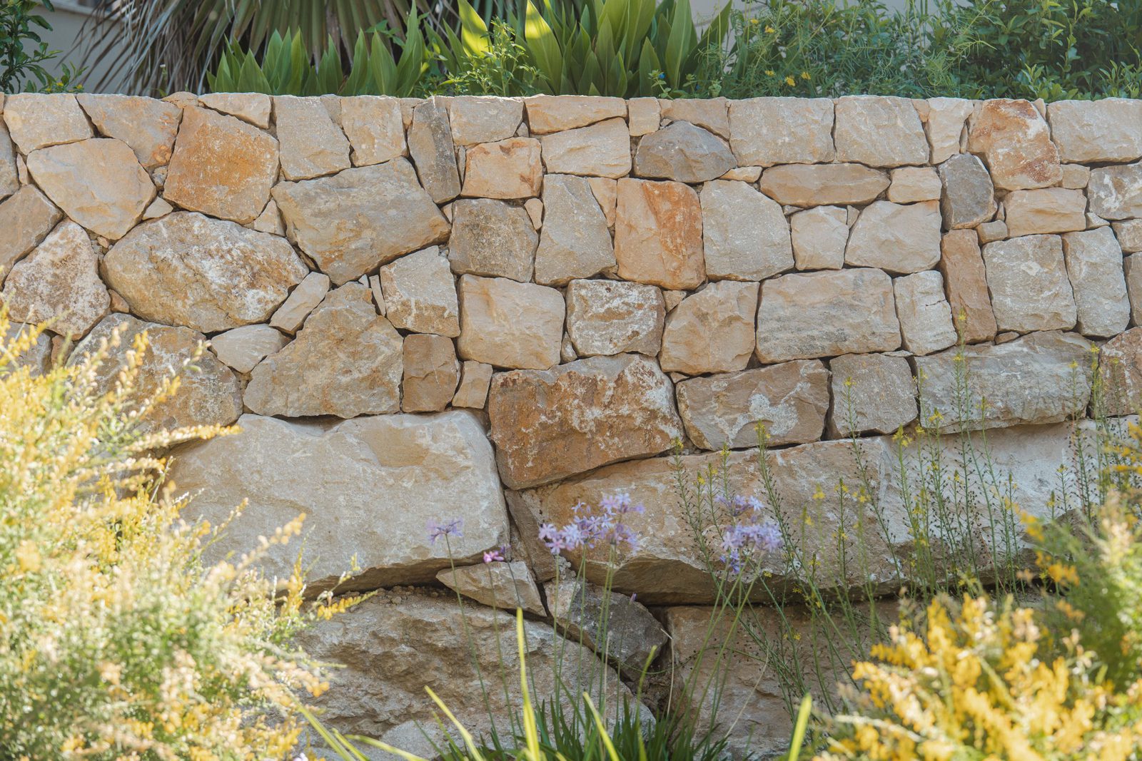 A stone wall and lush greenery surround a 5-bedroom villa in Altea - The Estates