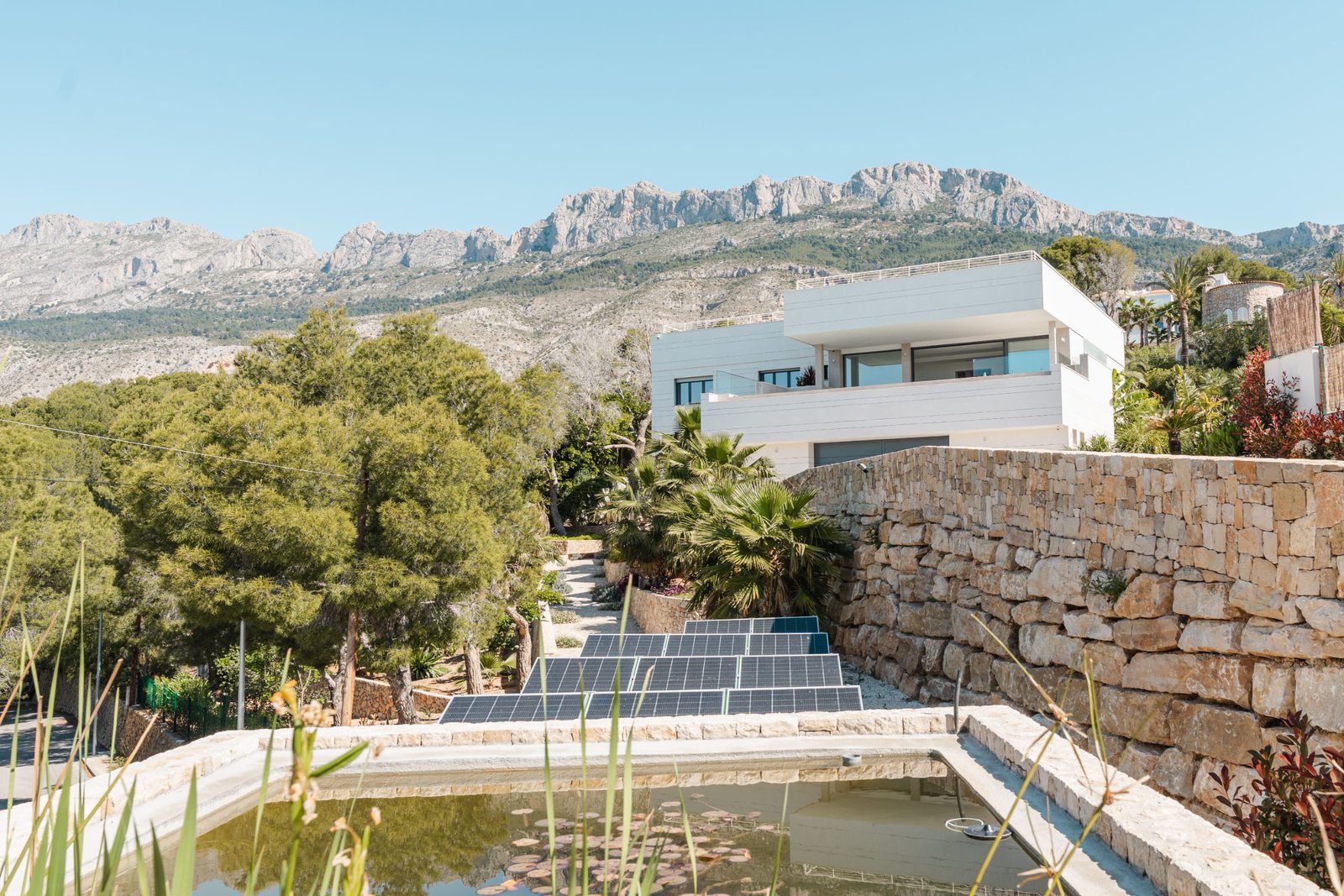 A modern villa with stunning mountain and sea views, featuring a pool and solar panels - The Estates