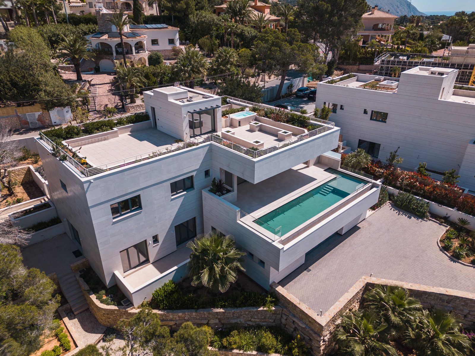 An aerial view of a modern 5-bedroom villa with a pool and lush greenery in Altea - The Estates