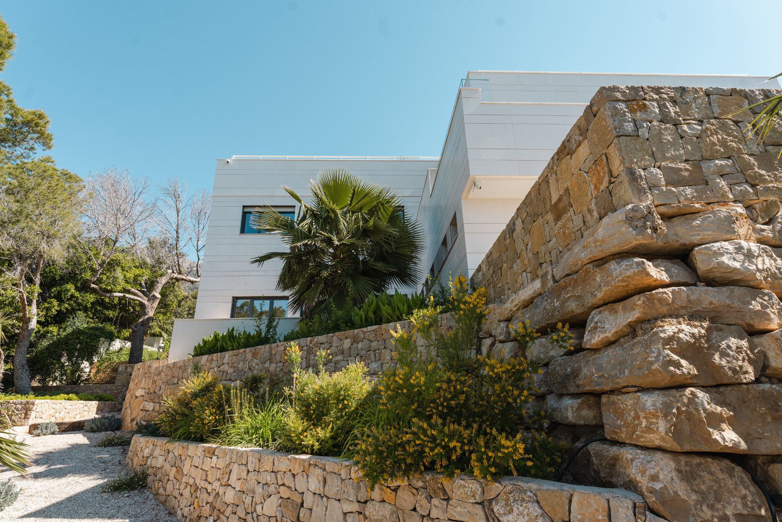 Modern villa exterior with stone walls and lush greenery in Altea - The Estates