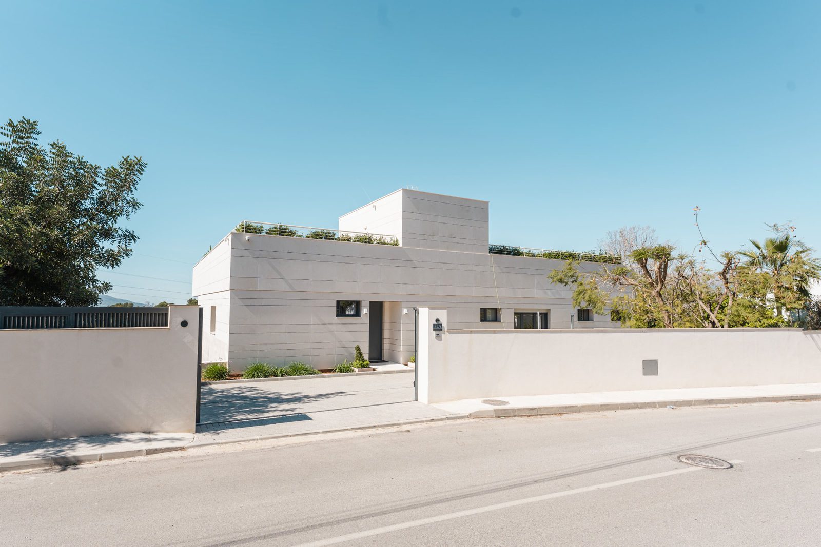 Modern villa exterior with a rooftop terrace and manicured gardens in Altea - The Estates