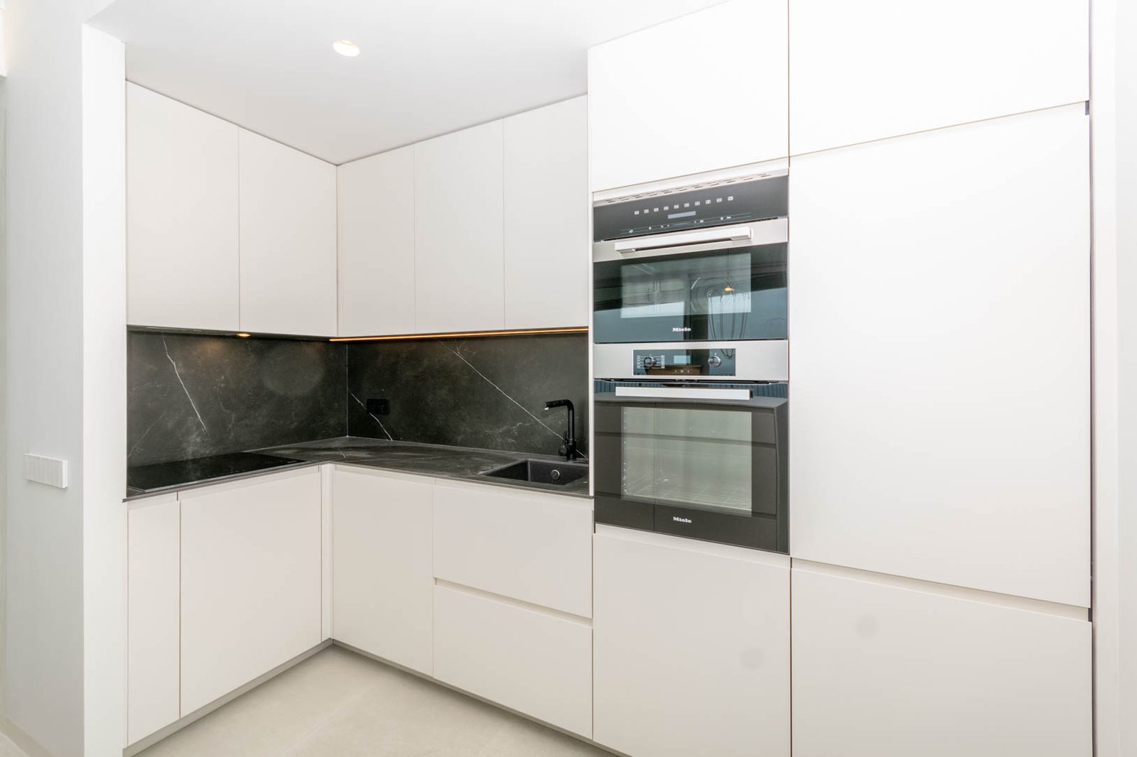 Modern kitchen with sleek white cabinets and dark marble backsplash in a 4-bedroom apartment in Calpe - The Estates