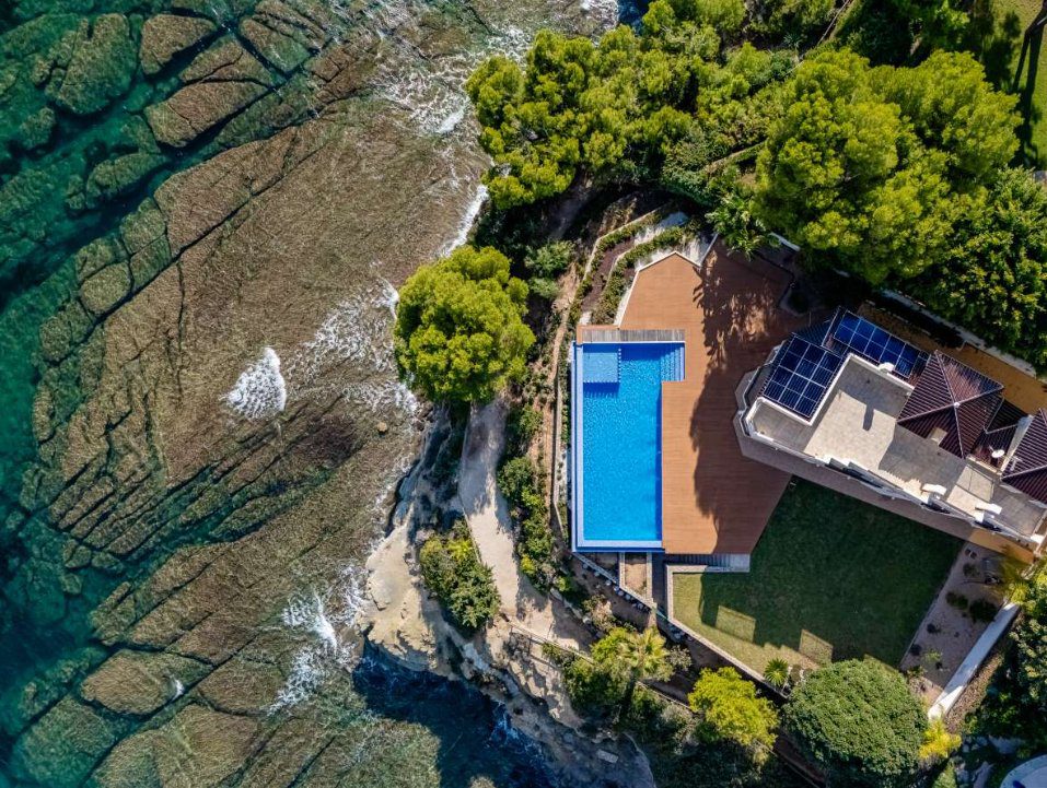 Aerial view of a villa with a pool and solar panels overlooking the sea in Calpe - The Estates