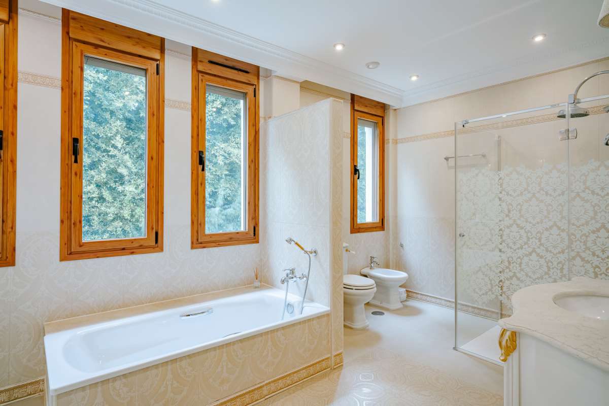 A luxurious bathroom with a large window view of a garden in a 6-bedroom villa in Calpe - The Estates