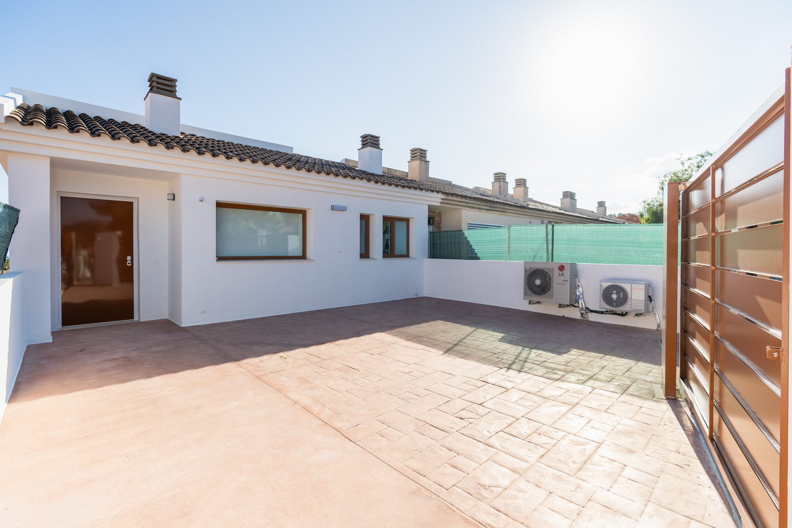 A rooftop terrace with a gate and air conditioning units on a 4-bedroom townhouse in La Nucía - The Estates