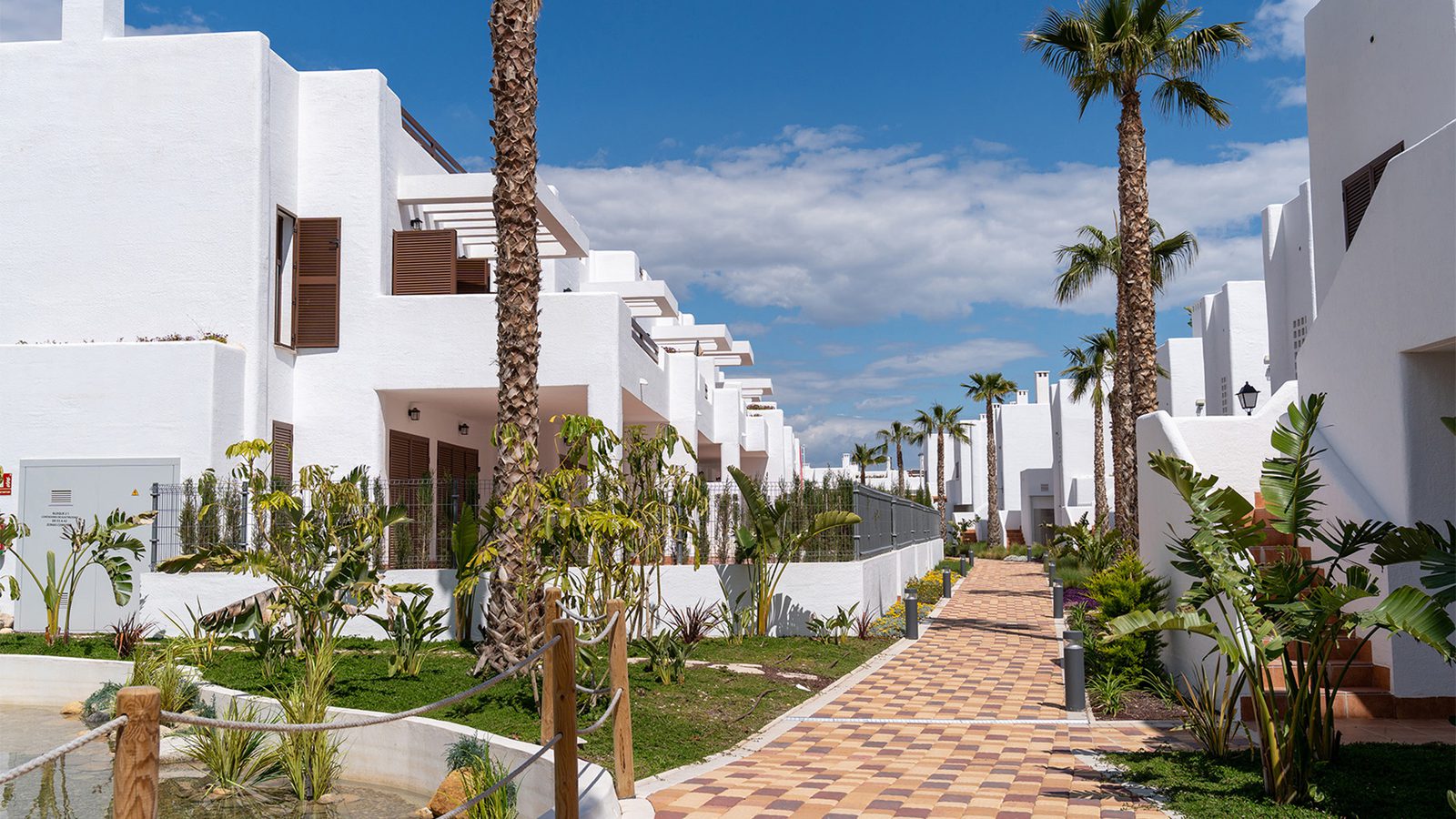 Exterior view of a 2-bedroom bungalow in Pulpí with palm trees and a pathway - The Estates