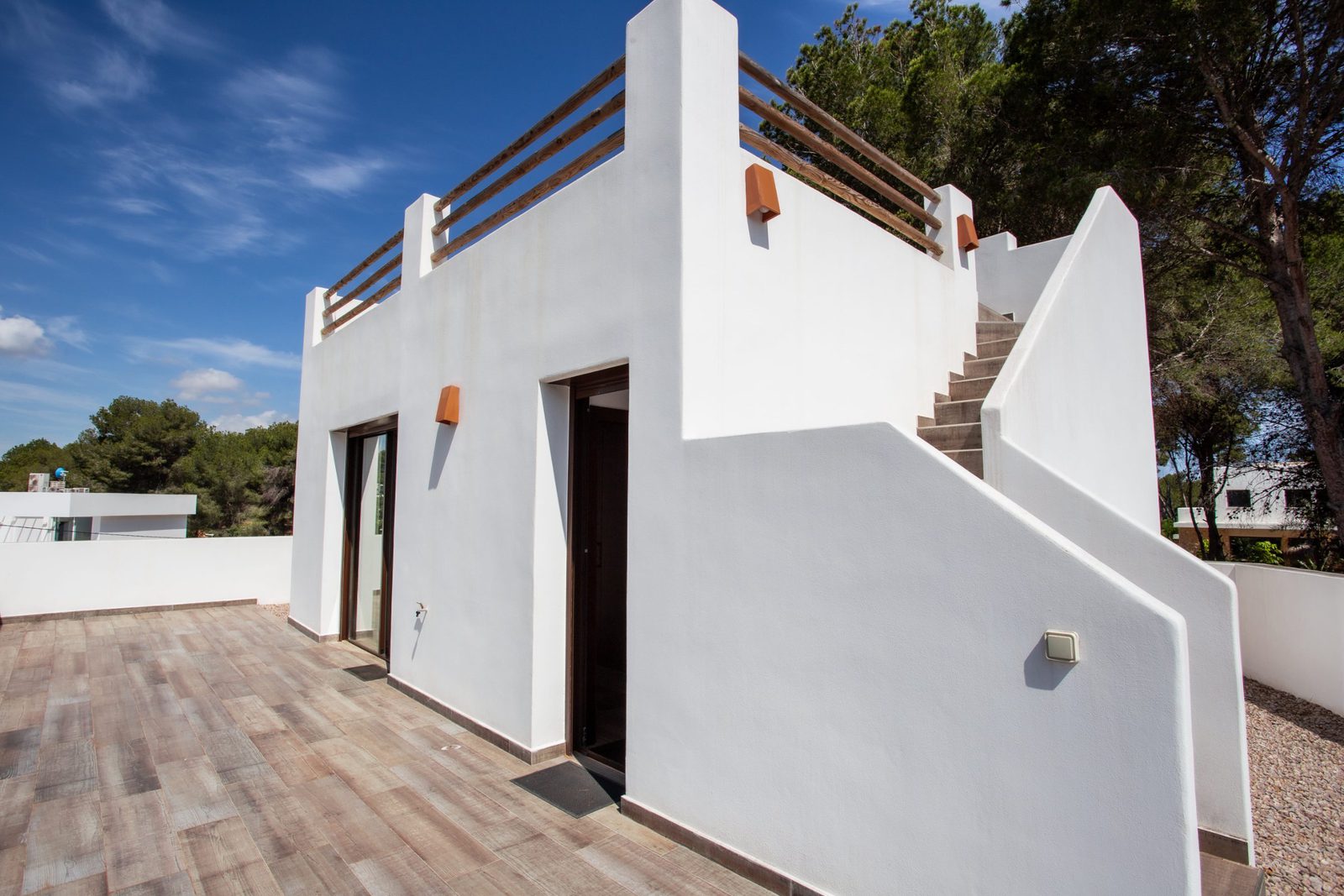 Exterior view of a 3-bedroom villa in Javea with a white facade and wooden staircase - The Estates