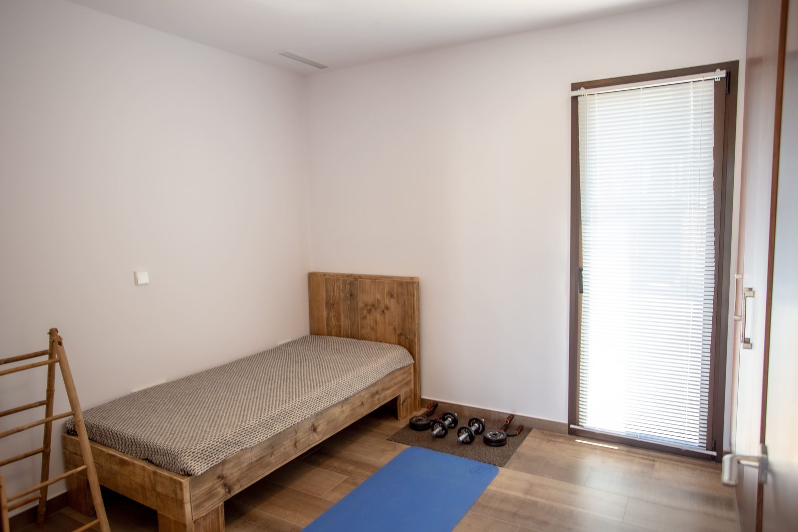 A bright bedroom with a wooden bed and window in a 3-bedroom villa in Javea - The Estates
