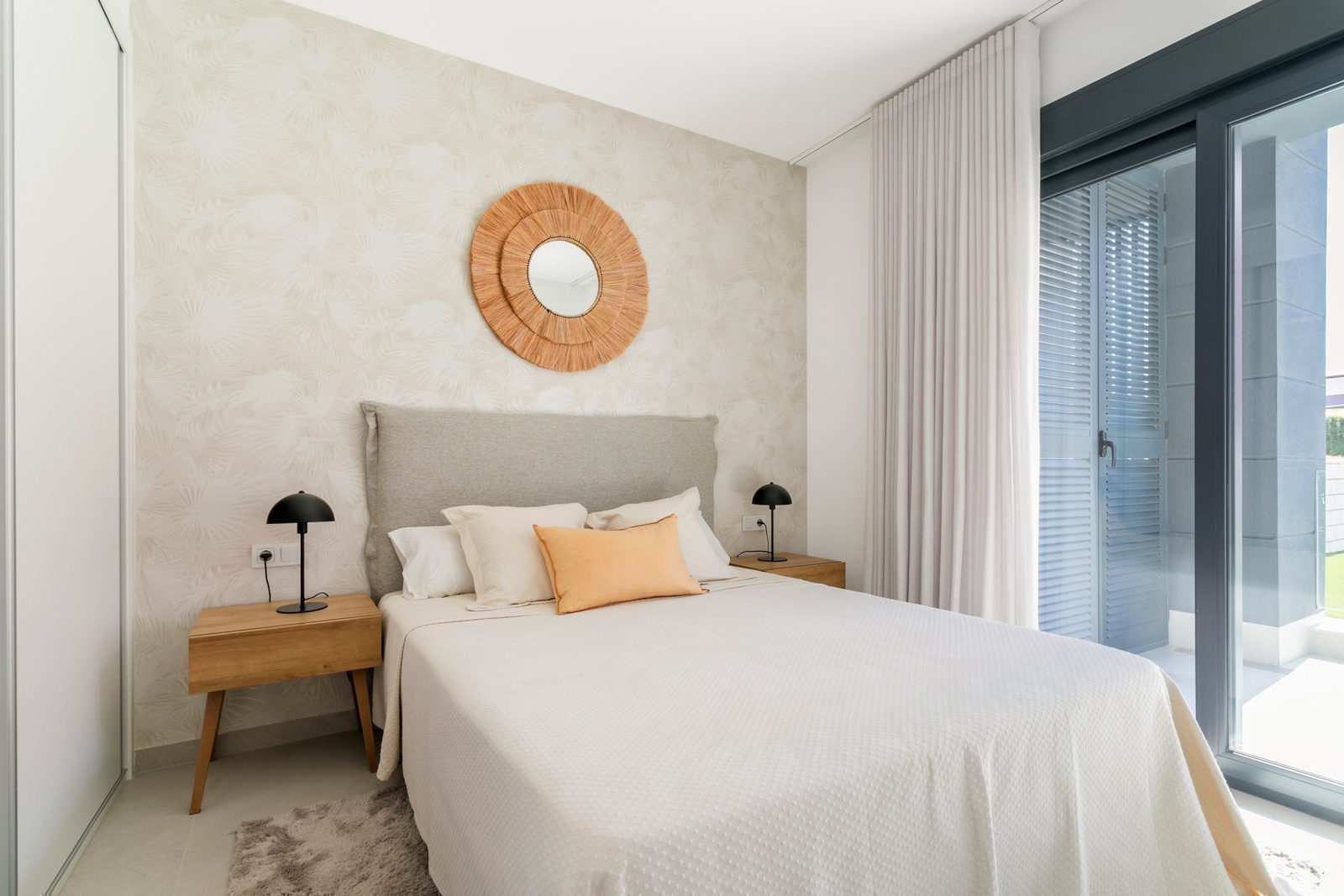 Stylish bedroom decor with a decorative mirror and patio doors in a 2-bedroom apartment in Torrevieja - The Estates