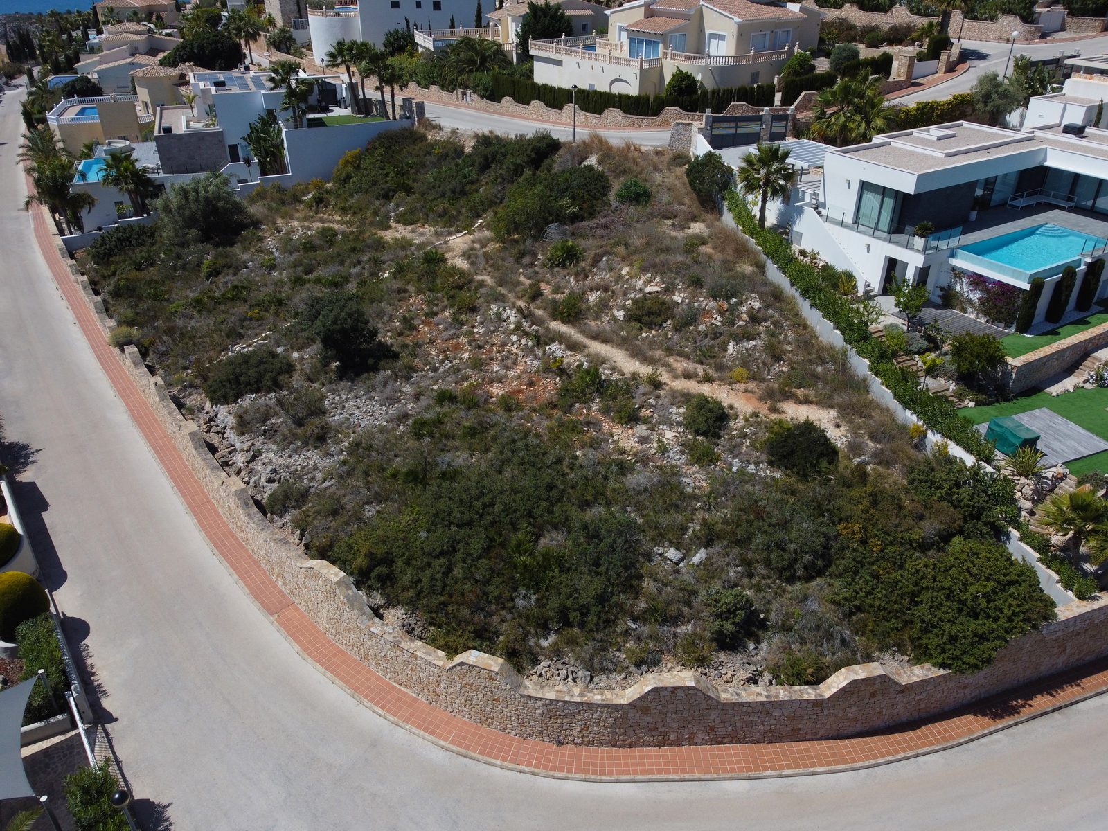 Aerial view of surrounding villas and rocky plot of a 3-bedroom villa in Benit