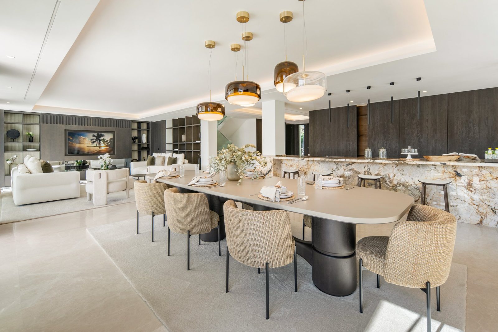 Open-plan dining area and kitchen with marble island, pendant lights and lounge seating in a 6-bedroom villa in Málaga - The Estates