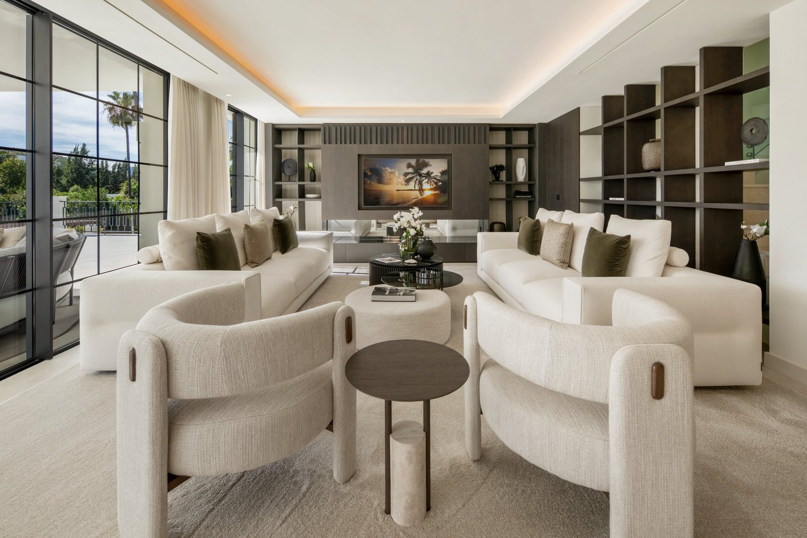 Elegant living room with sofas, armchairs and built-in shelving of a 6-bedroom villa in Málaga - The Estates