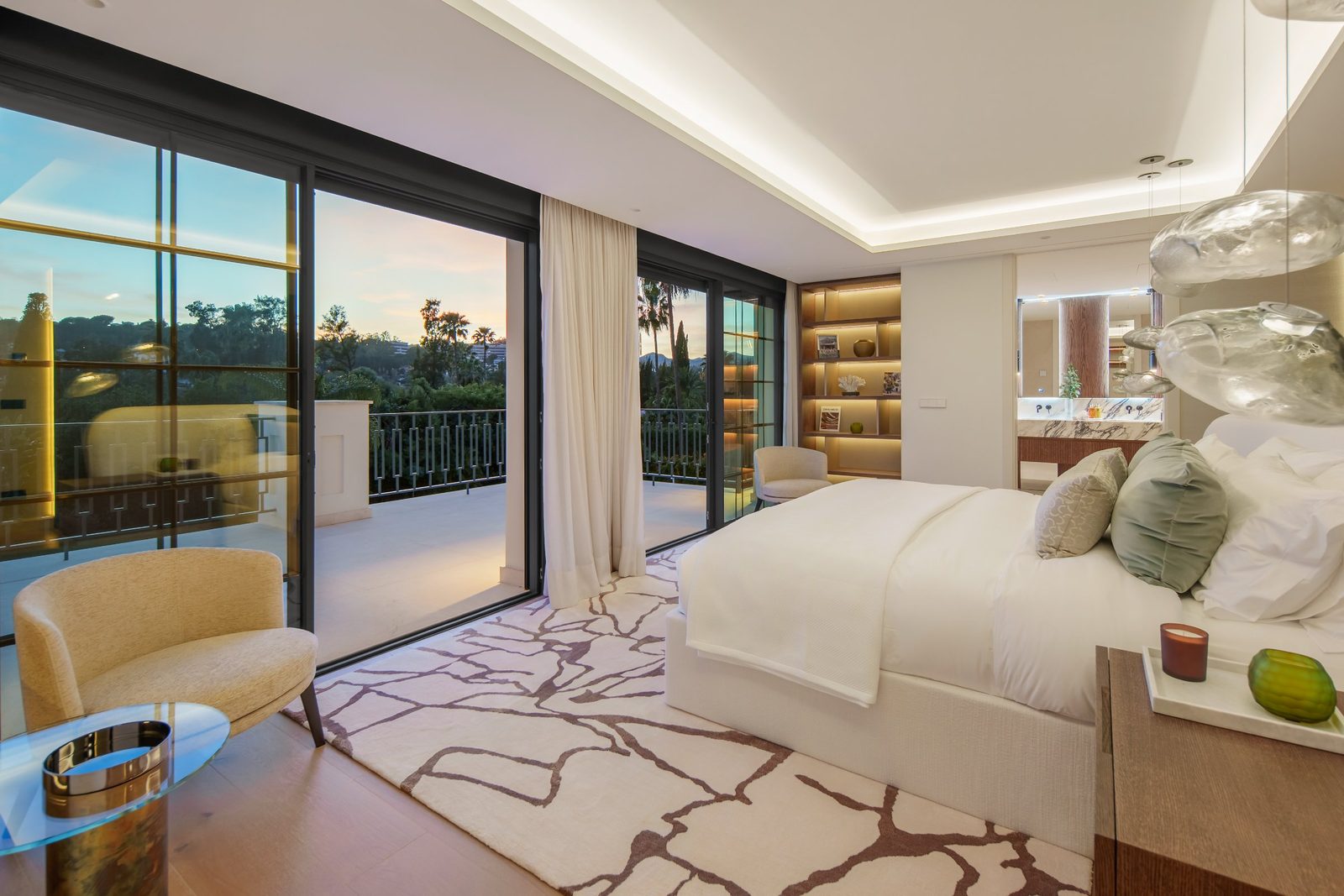 Elegant villa bedroom with terrace access, panoramic windows, upholstered bed and illuminated shelving in Nueva Andalucía, Marbella - The Estates