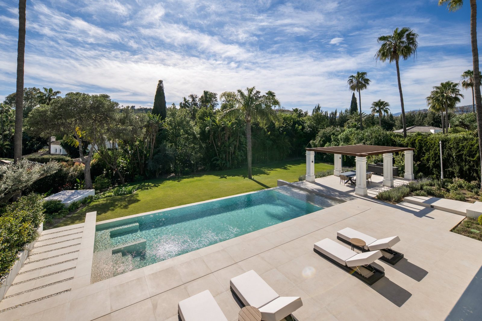 Outdoor swimming pool, sun terrace, pergola and landscaped garden of a 6-bedroom villa in Málaga - The Estates