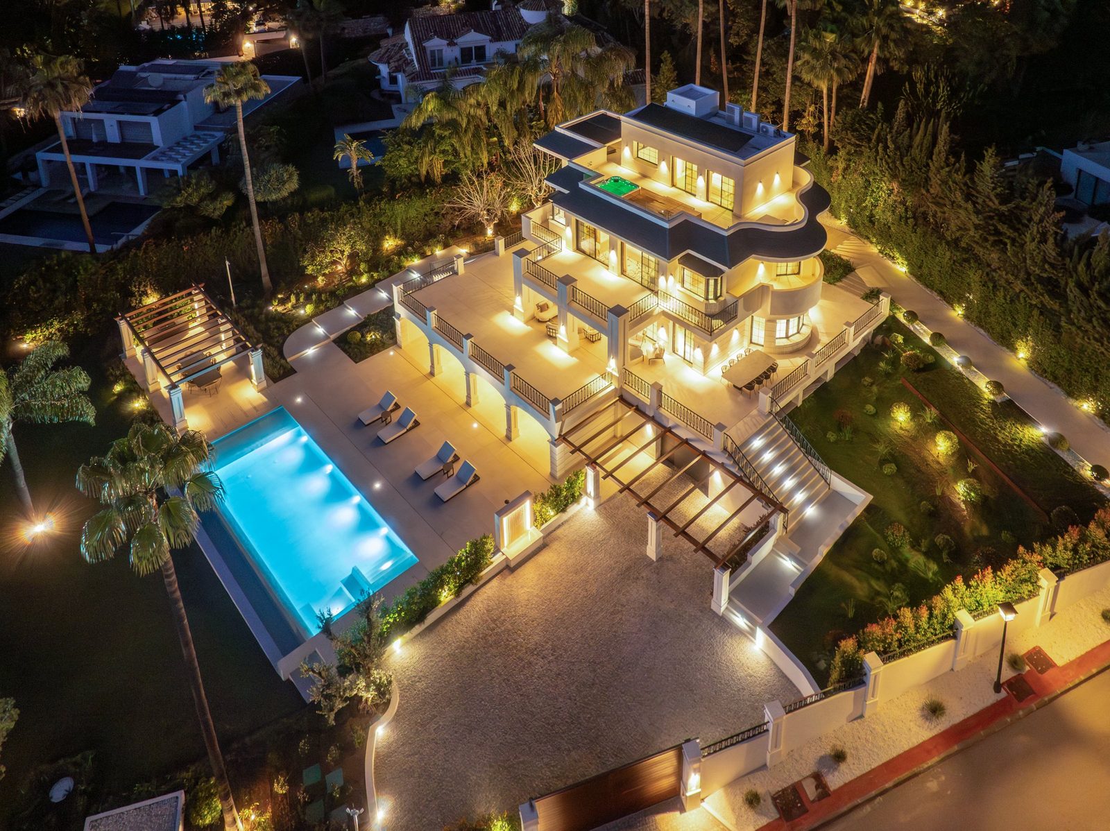 Aerial night view of a luxury villa with illuminated terraces, gardens and swimming pool in Marbella, Málaga - The Estates