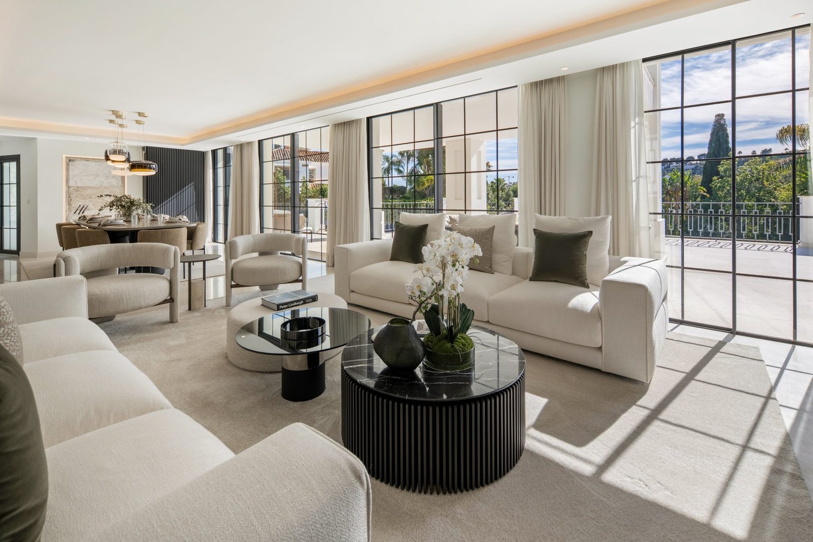 Bright modern living room with cream seating, dining area and terrace views through floor-to-ceiling windows