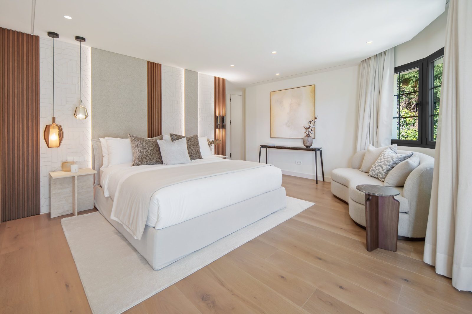 Contemporary bedroom with upholstered king bed, lounge chair, wood flooring and garden views in a 6-bedroom villa in Málaga - The Estates