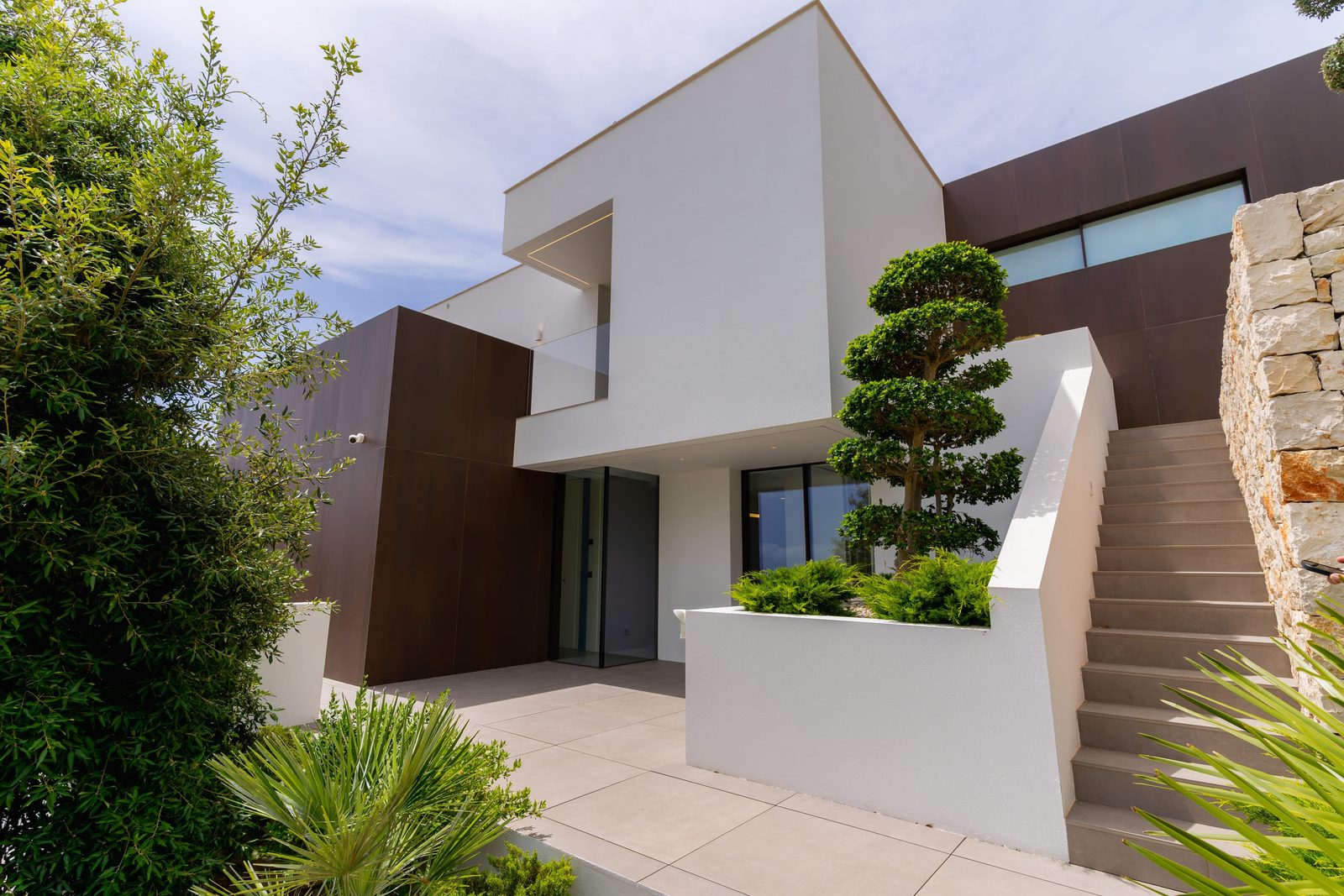 Modern exterior of a 5-bedroom villa in Benitachell with lush landscaping - The Estates