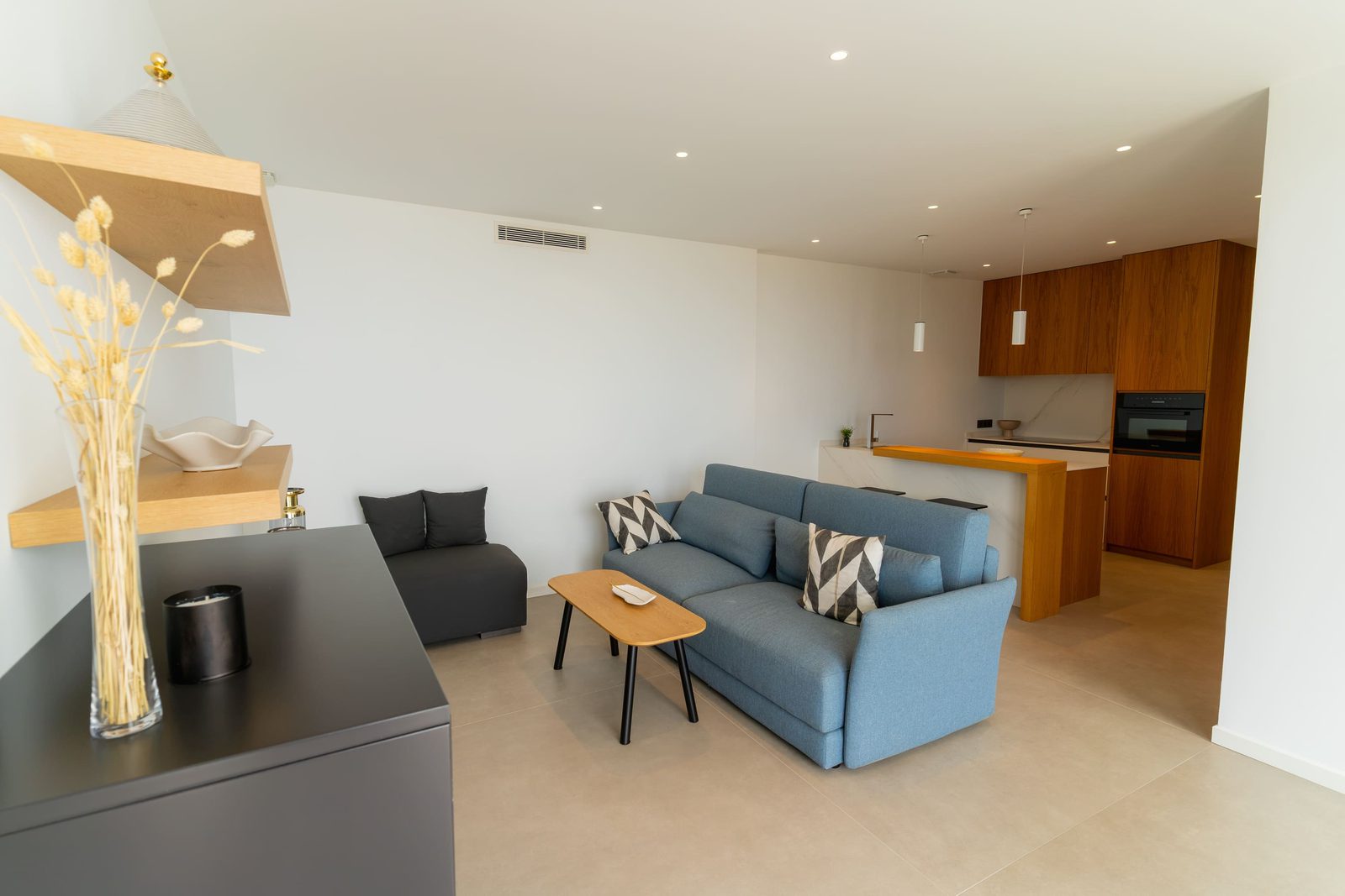 A modern living area with a sofa and kitchen in a 5-bedroom villa in Benitachell - The Estates