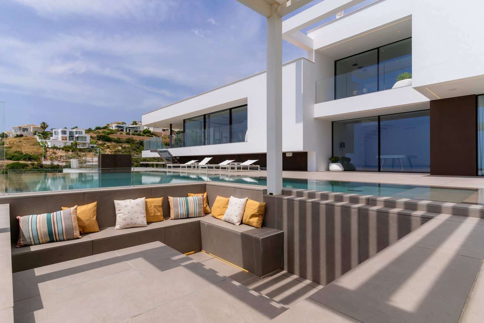 A modern pool area with seating and sun loungers at a 5-bedroom villa in Benitachell - The Estates