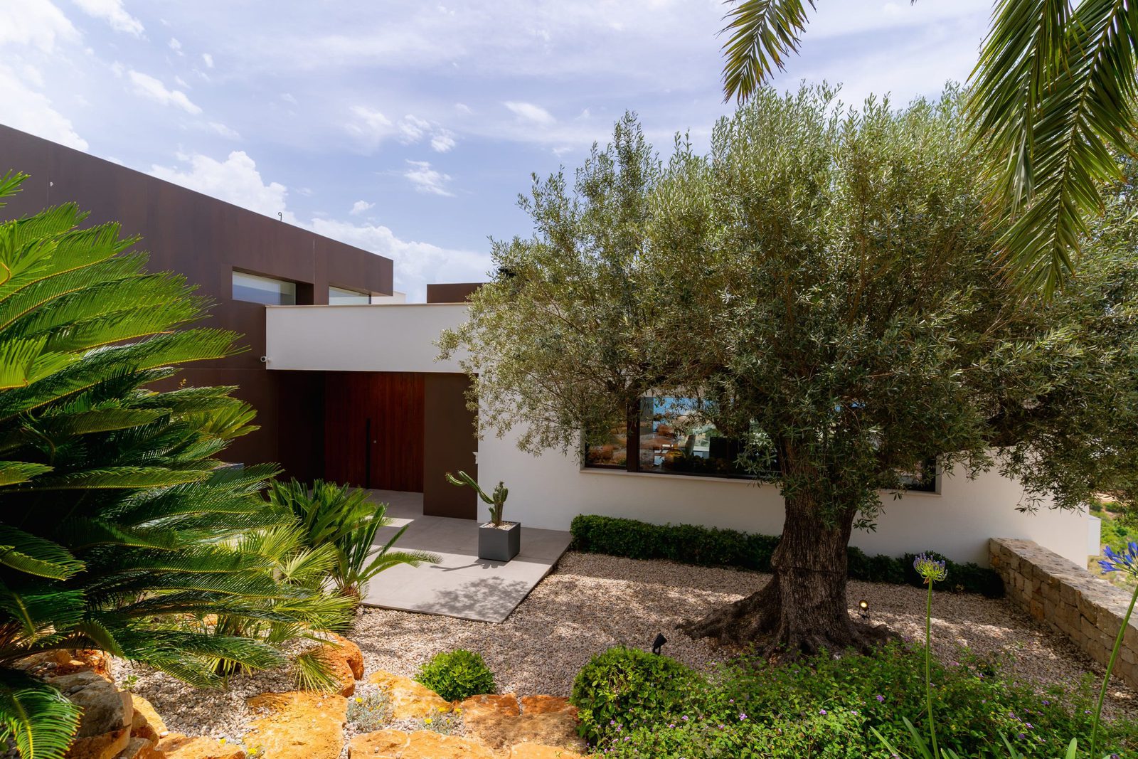 Exterior view of a 5-bedroom villa in Benitachell with lush landscaping and sea views - The Estates