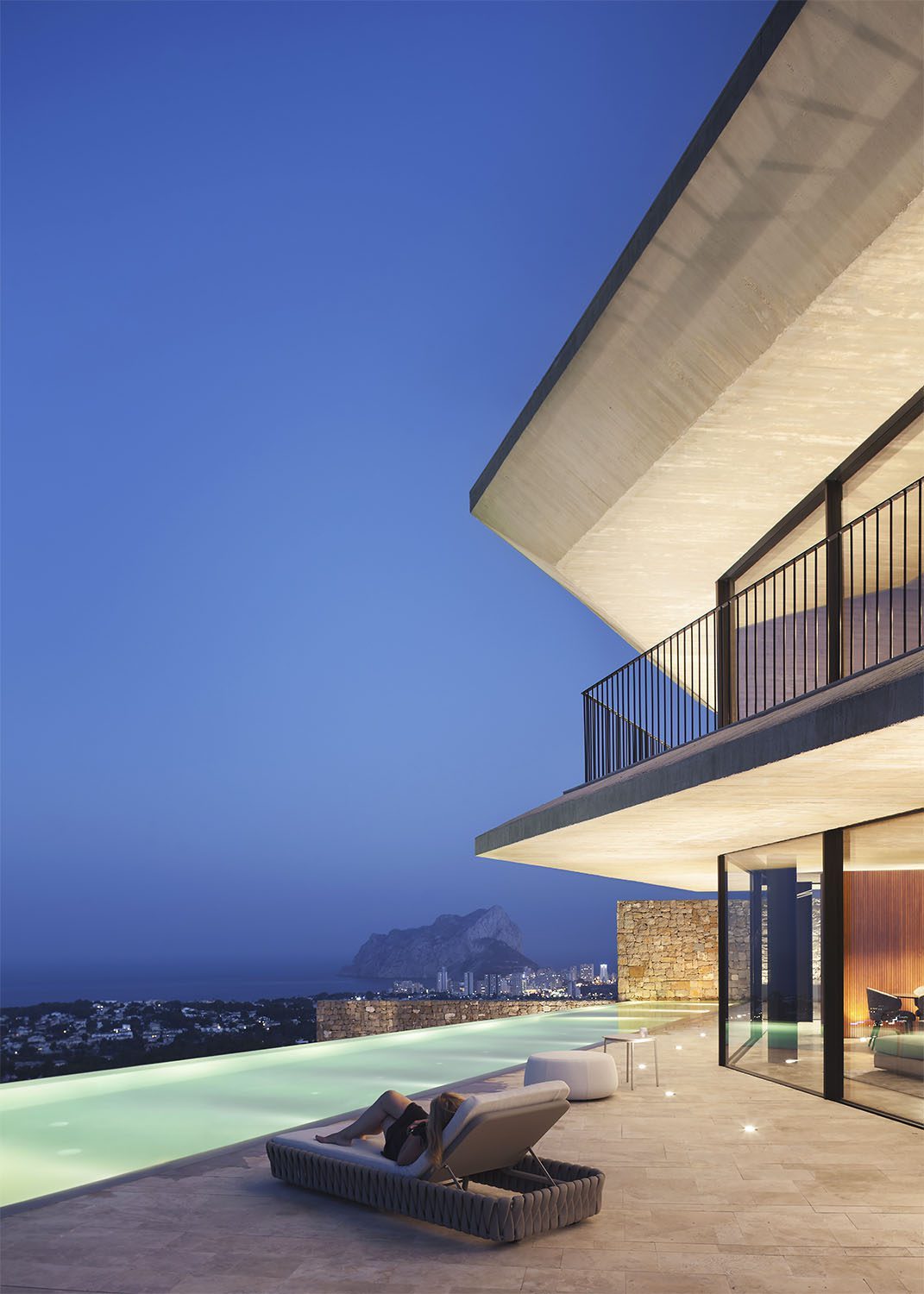 Contemporary villa terrace with infinity pool and panoramic sea and mountain views at dusk of a 4-bedroom villa in Benissa - The Estates