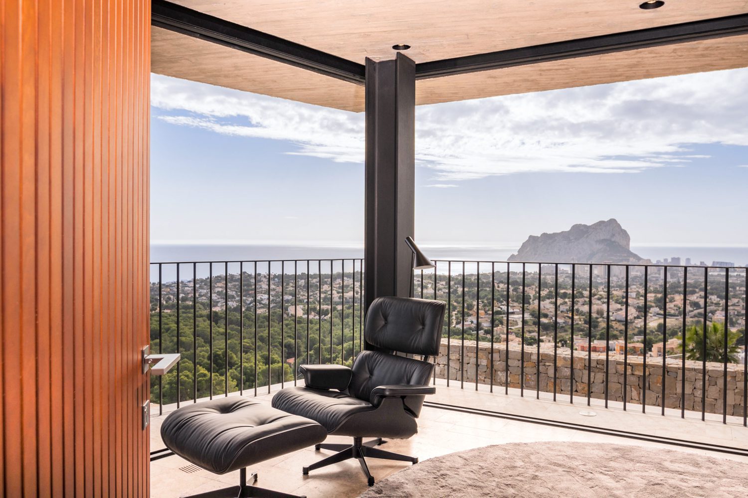 Covered terrace with lounge chair overlooking panoramic sea views and Peñón de Ifach at a 4-bedroom villa in Benissa - The Estates