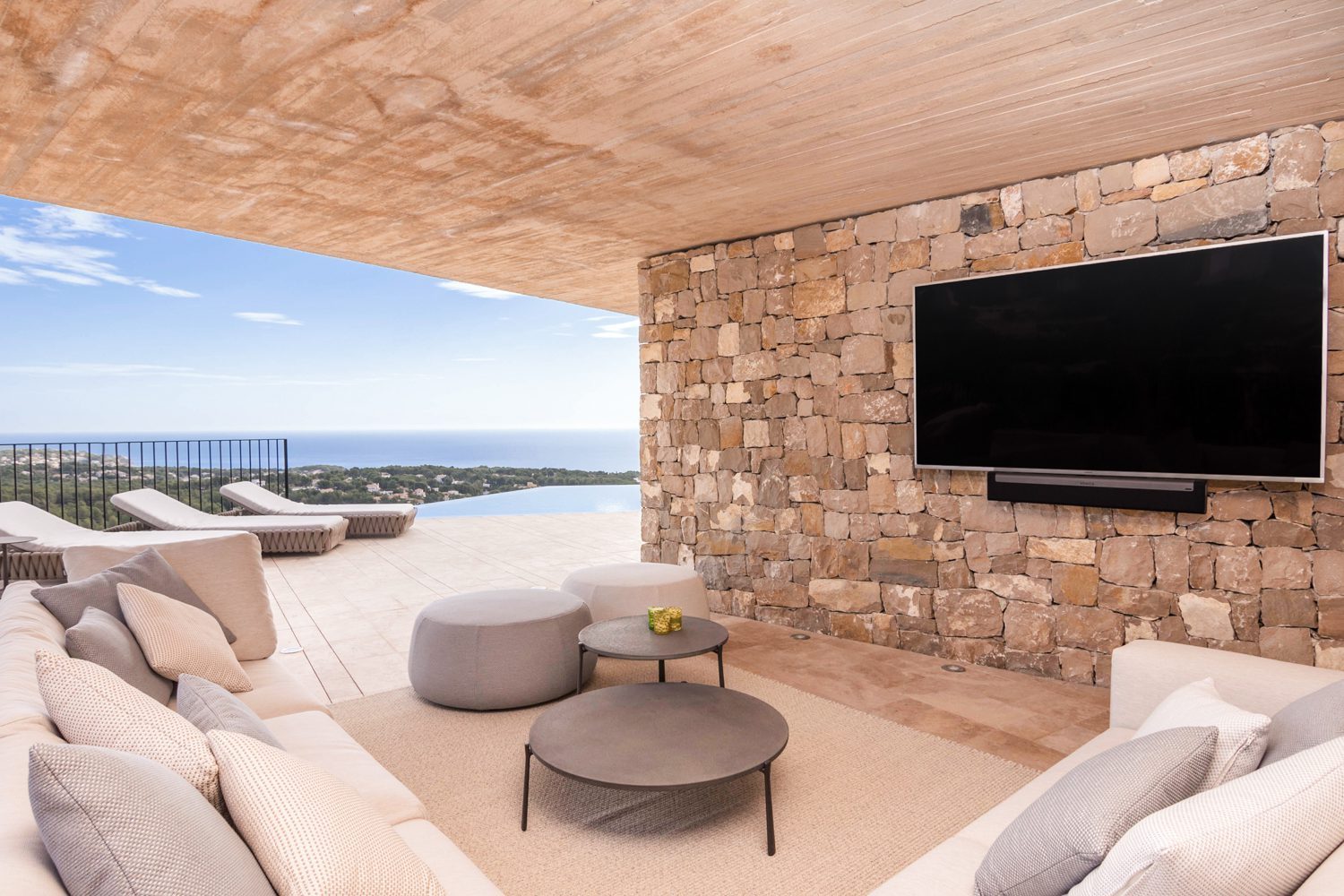 Covered terrace lounge with stone wall, TV and panoramic sea views of a 4-bedroom villa in Benissa - The Estates