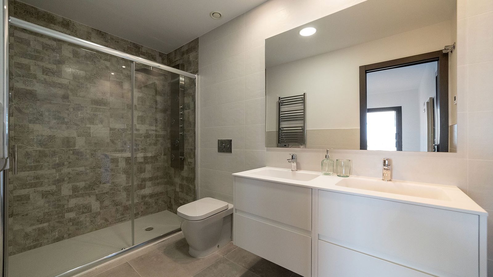 Modern bathroom with walk-in shower, wall-mounted toilet and double vanity in a 3-bedroom bungalow in Pulpí - The Estates