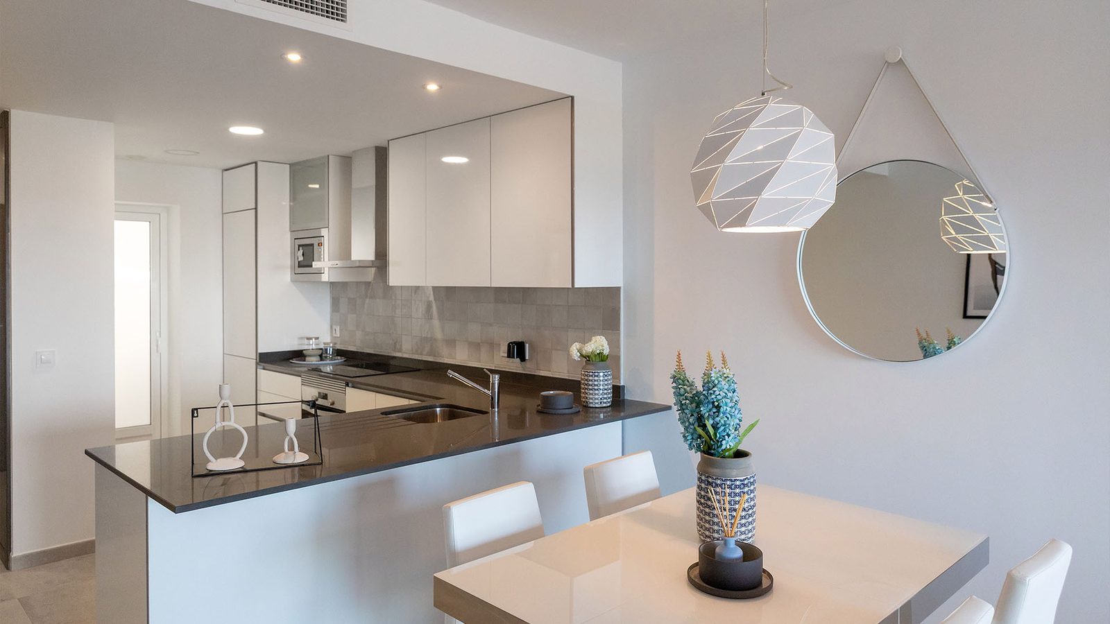 Modern open-plan kitchen and dining area with white cabinetry, breakfast bar and pendant lighting in a 3-bedroom bungalow in Pulpí - The Estates
