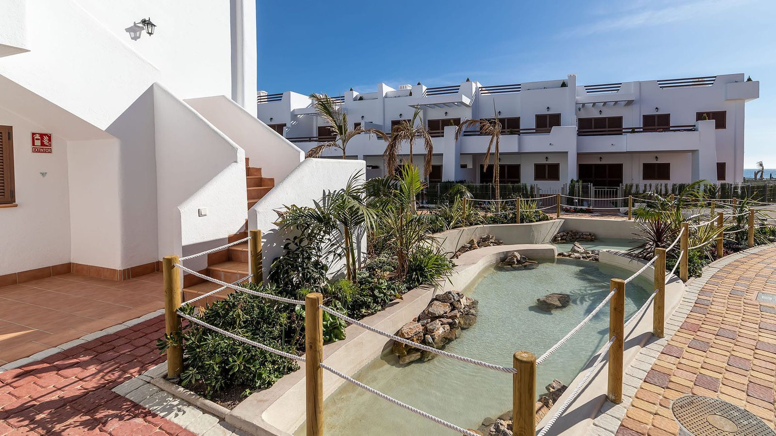 Landscaped courtyard with a shallow water feature and palm-lined pathways at a 3-bedroom bungalow in Pulpí - The Estates