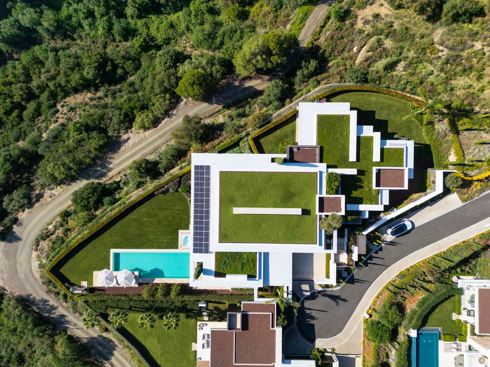 Aerial view of a modern villa with rooftop gardens, swimming pool and landscaped grounds in Benahavís, Málaga - The Estates
