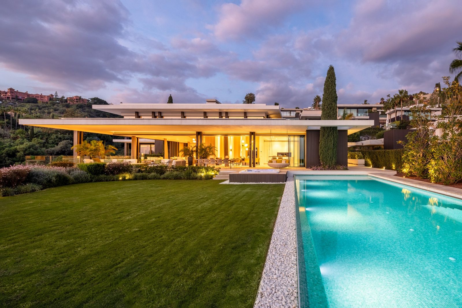 Contemporary villa with illuminated interiors, landscaped garden and swimming pool at dusk of a 6-bedroom villa in Málaga — The