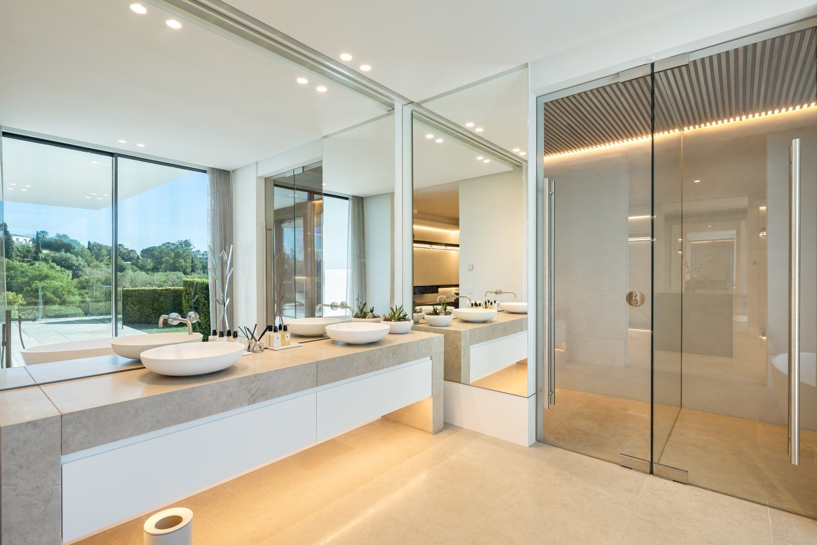Contemporary bathroom with double vanity, mirrored walls and glass shower of a 6-bedroom villa in Málaga - The Estates