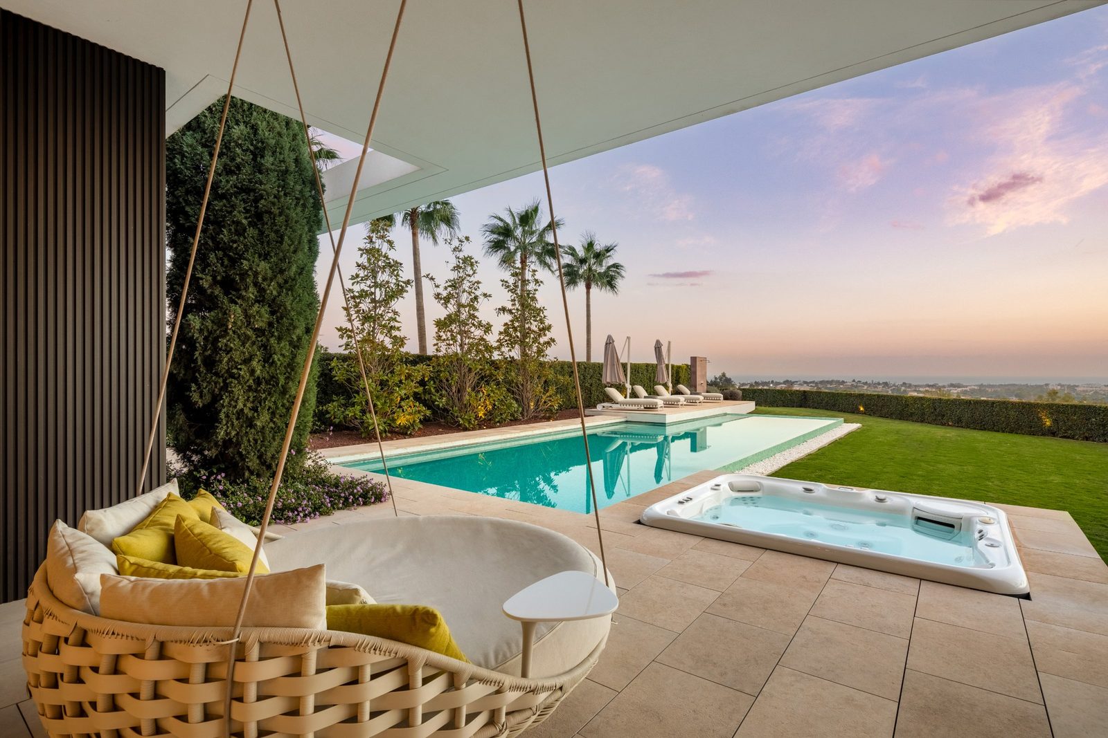 Covered terrace with hanging chair, pool, hot tub, landscaped garden and sea views of a 6-bedroom villa in Málaga - The Estates