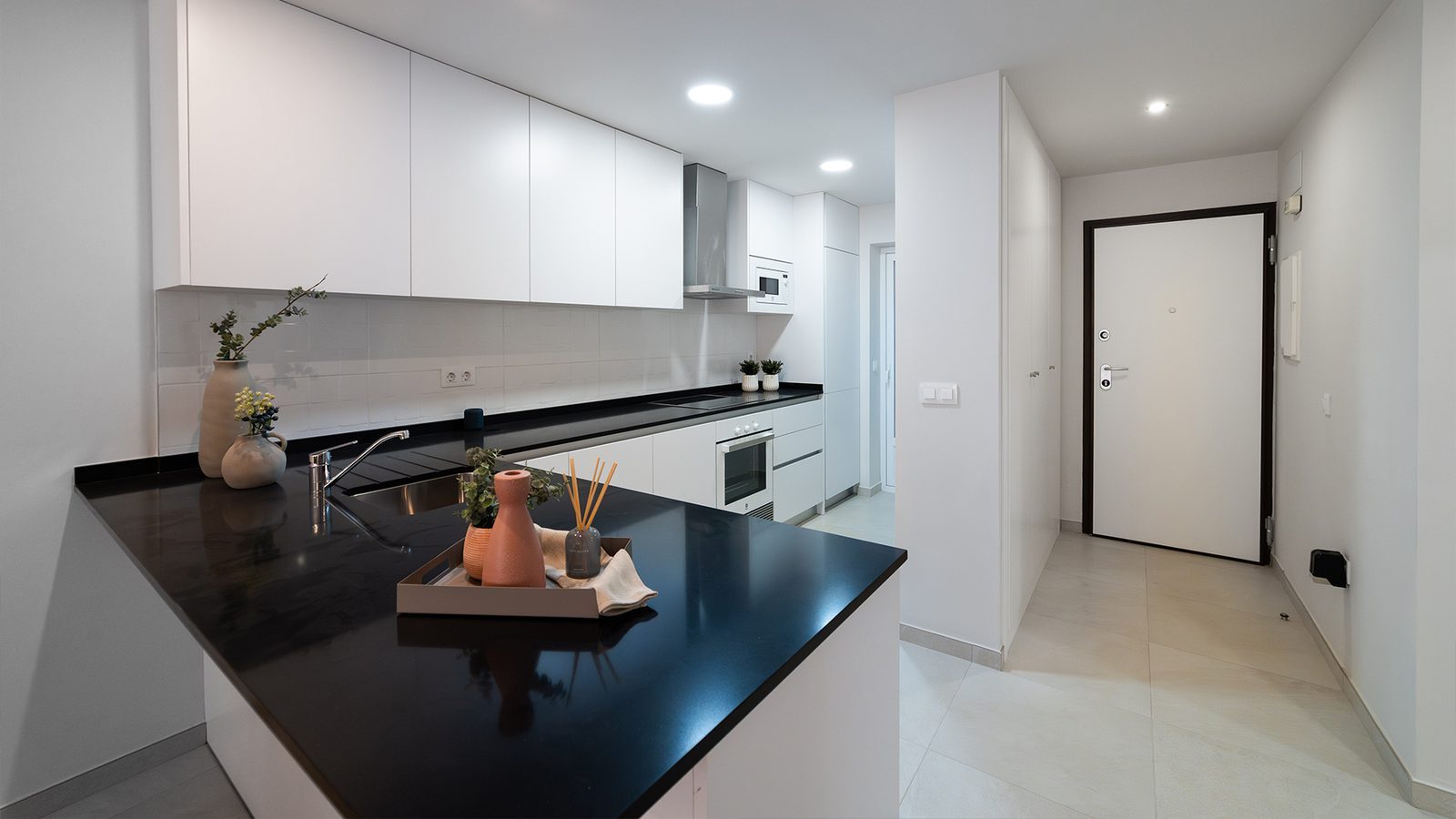 Modern kitchen with black worktops, white cabinets and hallway entrance in a 2-bedroom bungalow in Pulpí - The Estates