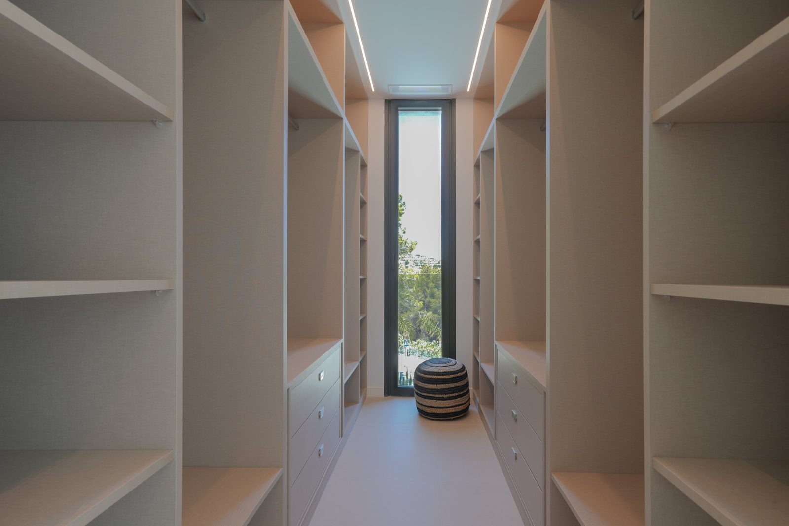 A spacious walk-in wardrobe with a window overlooking the countryside in a 4-bedroom villa in Moraira - The Estates