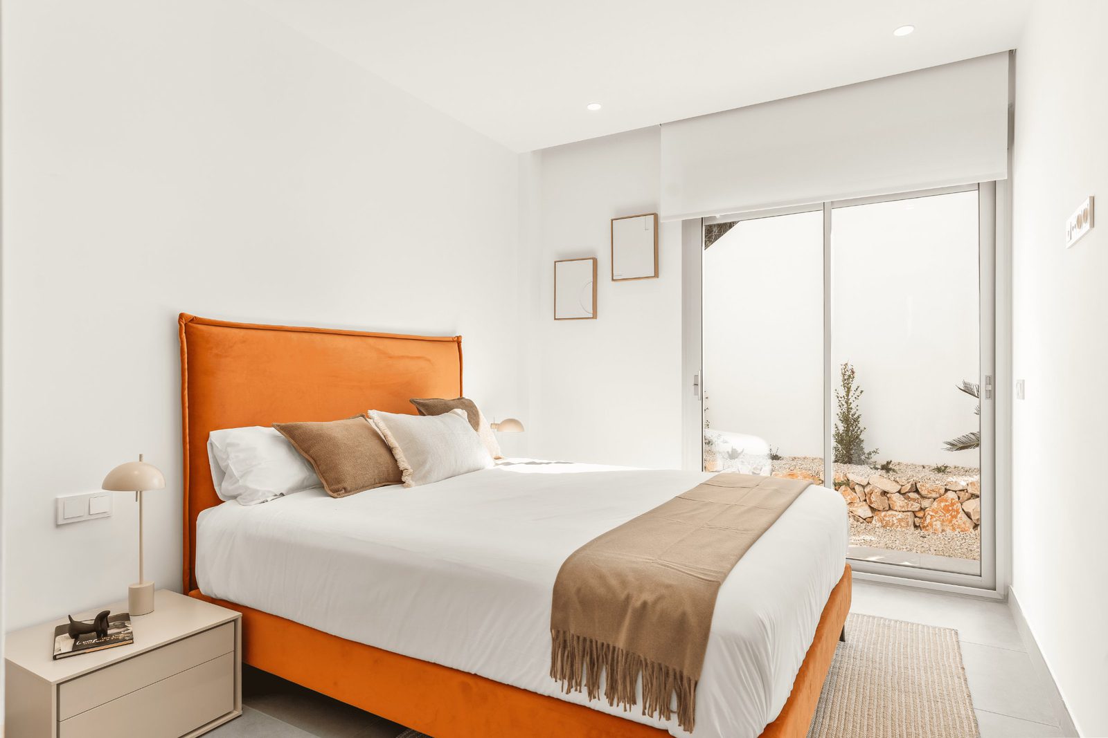 A stylish bedroom with a large bed and patio doors overlooking the sea in a 3-bedroom villa in Benitachell - The Estates