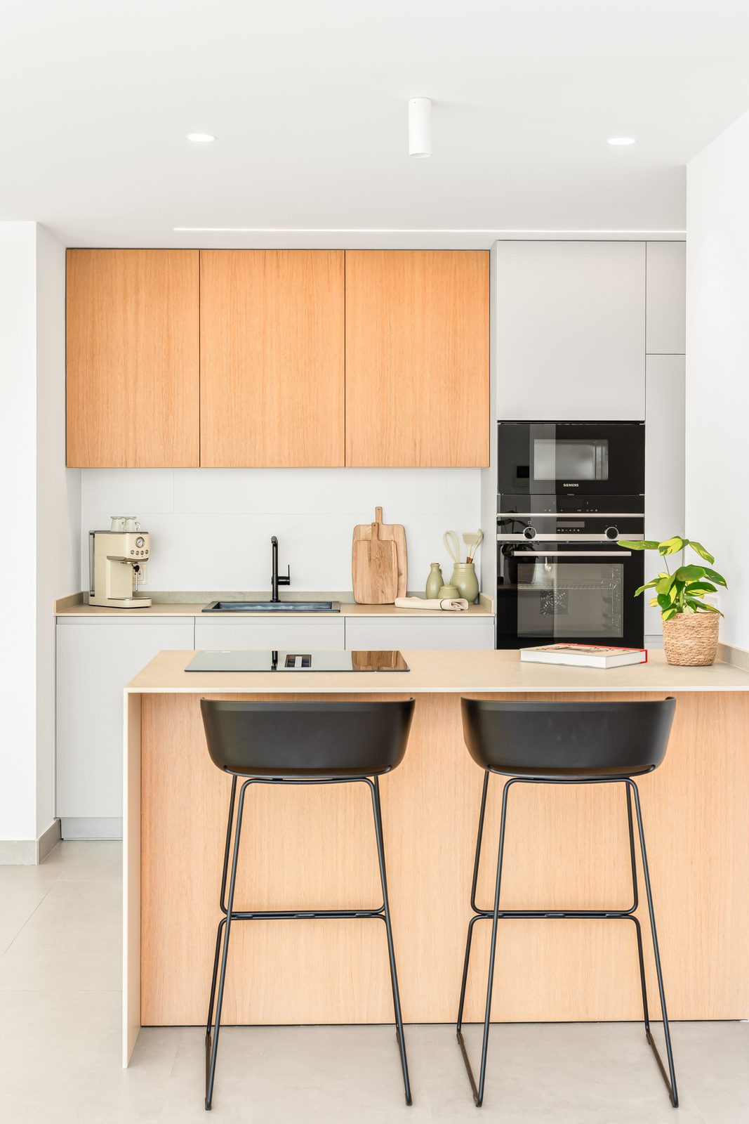 Modern kitchen with wooden cabinets and bar stools in a 3-bedroom villa in Benitachell - The Estates