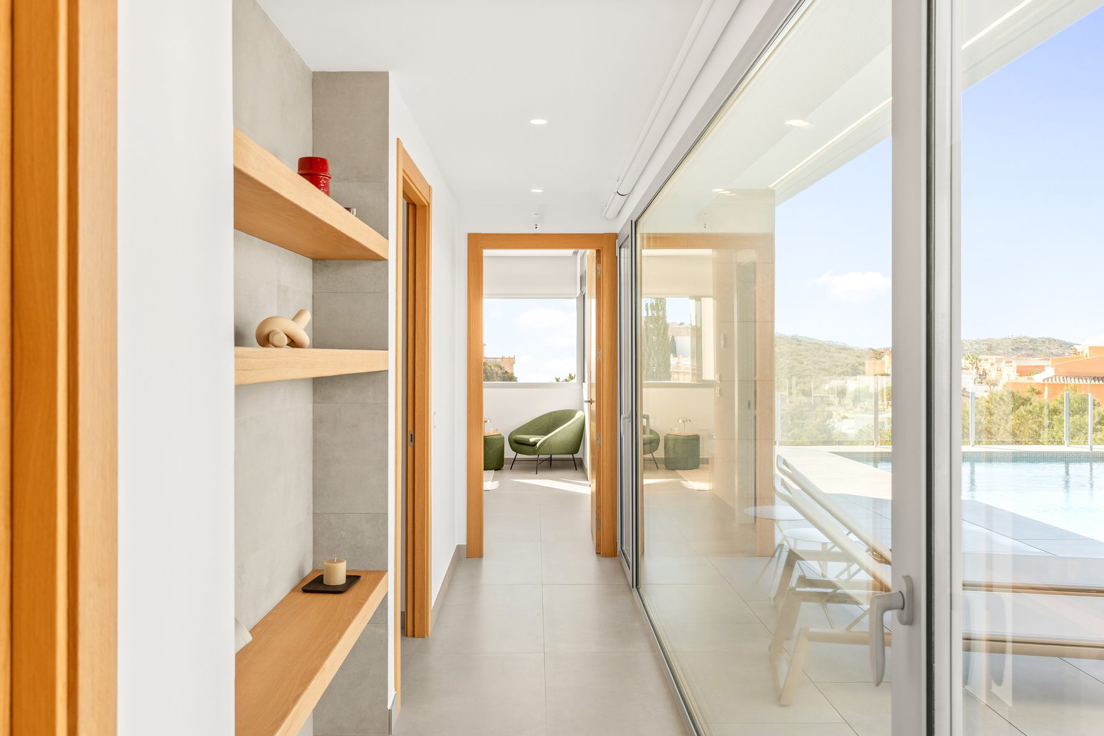 Modern hallway with shelving and sliding doors leading to a terrace and sea view - The Estates