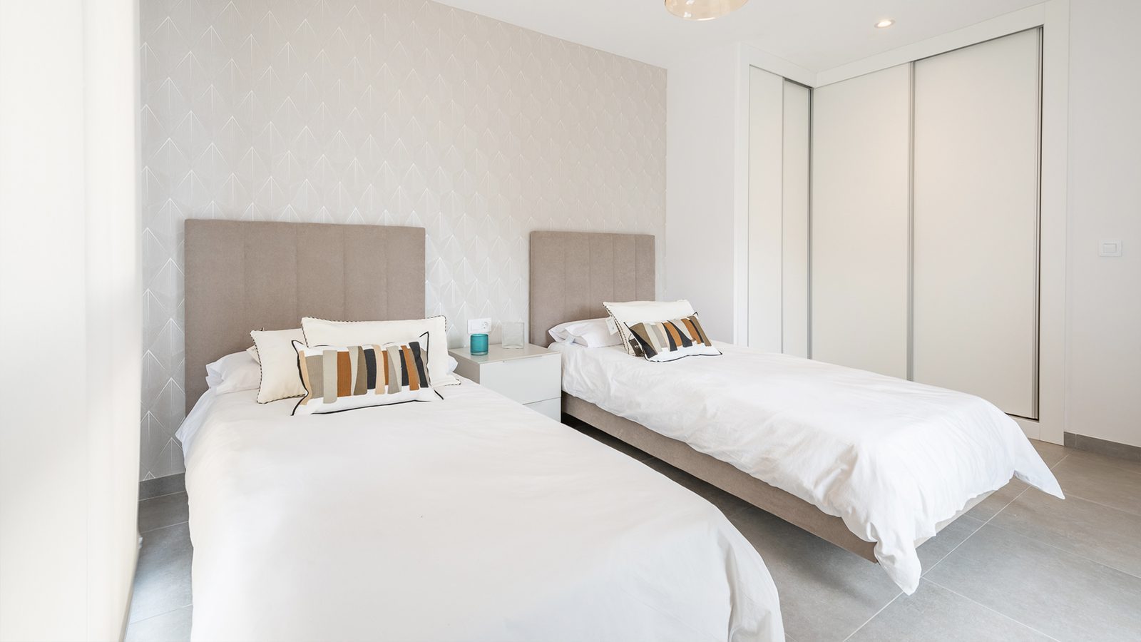 Twin bedroom with patterned feature wall and fitted wardrobes in a 3-bedroom semi-detached in Capdepera - The Estates