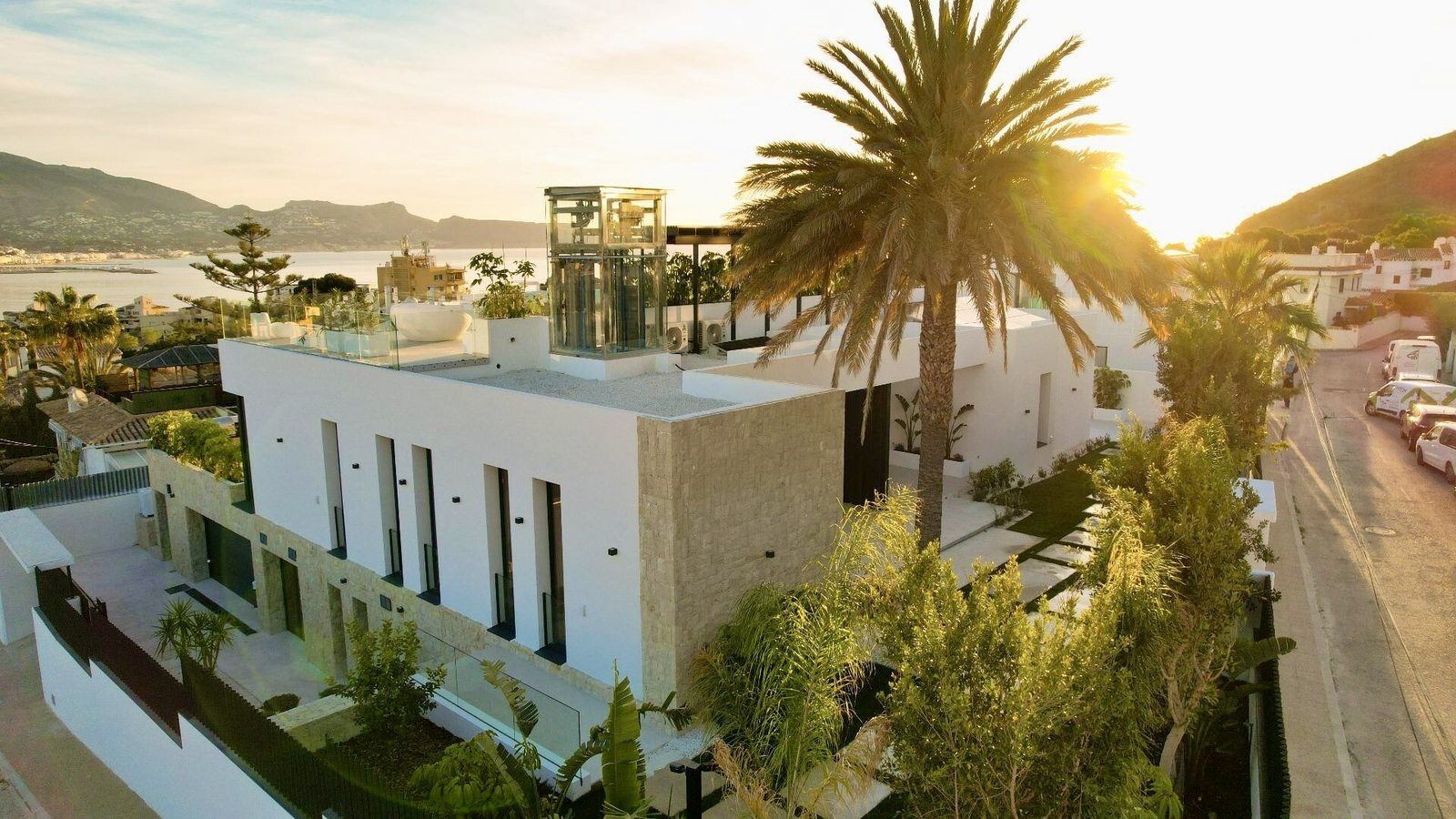 A modern villa with sea views and palm trees at sunset in La Nucia - The Estates